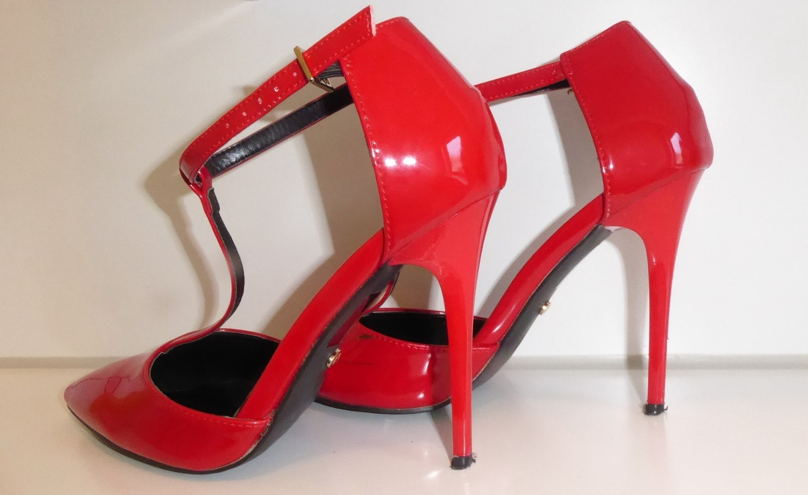 High heels patent leather strappy pumps in neon red worn well worn