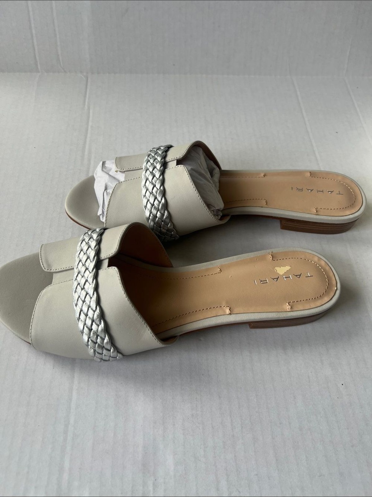 Tahari «Amorie» slide sandals featuring white leather upper silver braided strap