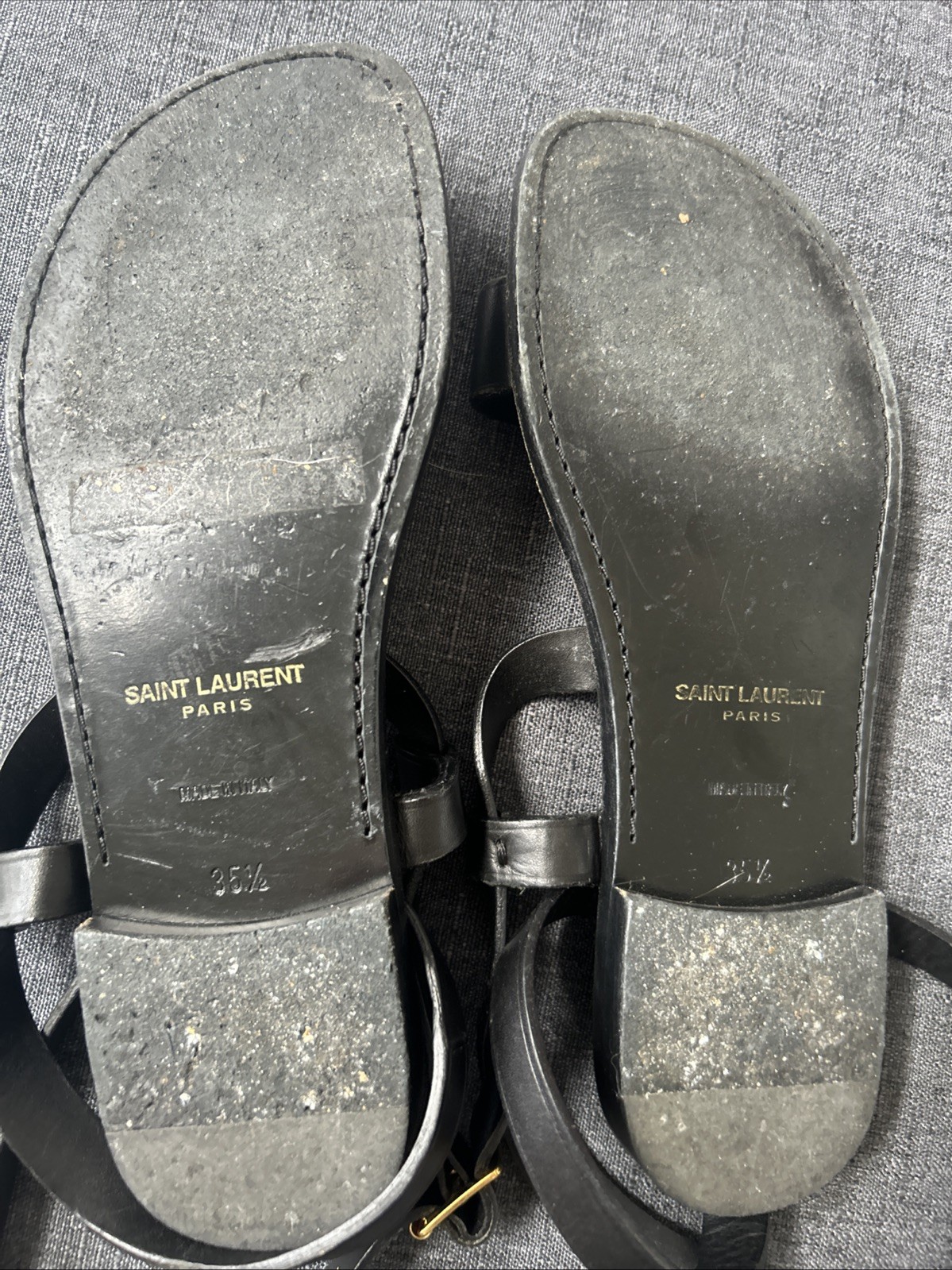 Black leather Saint Laurent sandals feature gold-tone studded accents. Size 35.5